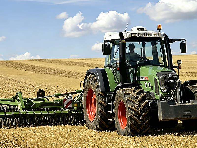 Farm tractor with tillage implement working in harvested wheat field