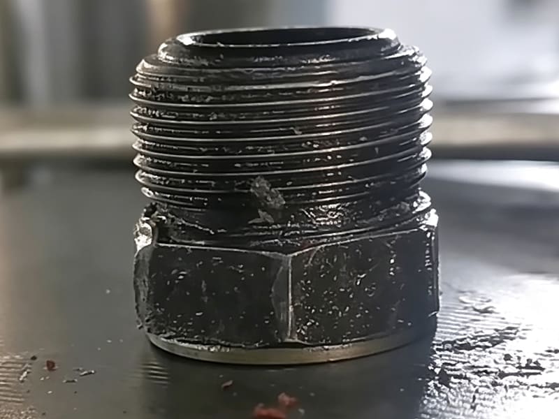 Close-up photo of cracked male thread hydraulic pipe fitting, metal fatigue damage on hydraulic cylinder pipeline connector, oil leakage risk failure component