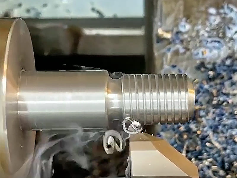 Close-up view of CNC lathe metal thread turning, precision thread turning machining for hydraulic cylinder piston rod, metal chip cutting scene