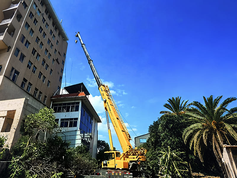 Mobile truck crane lifting operation on construction site beside building