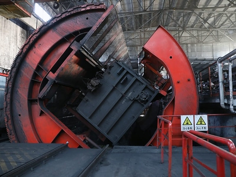 Large red rotary railcar dumper equipment inside industrial plant workshop