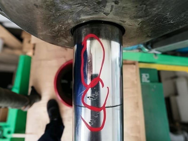Close‑up photo of damaged scratched chrome plated piston rod marked in red