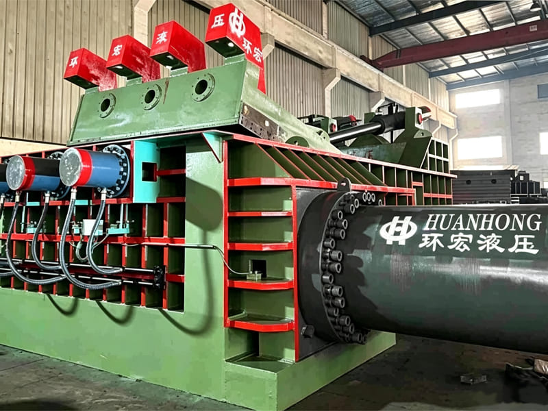 Industrial scrap metal baler machine equipped with large hydraulic cylinders in factory workshop