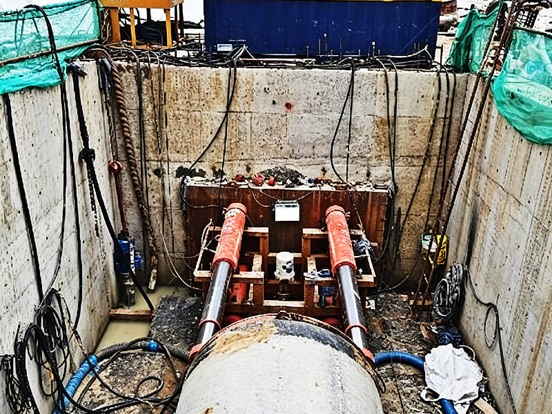 Two large hydraulic jacking cylinders used in underground pipe jacking construction pit