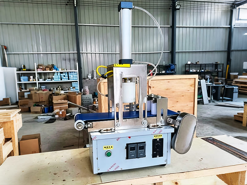 Bench‑top pneumatic automatic pressing machine with conveyor belt in workshop