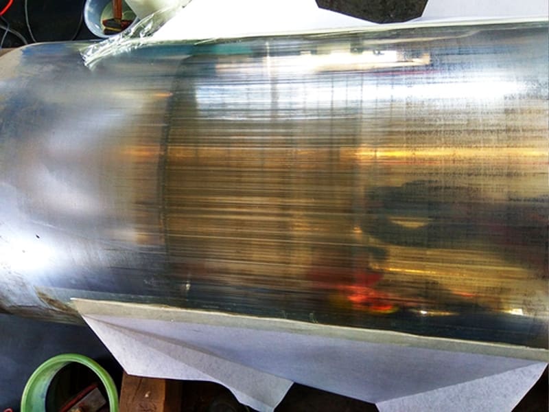 Close‑up photo of damaged hydraulic cylinder piston rod with longitudinal scratch marks on chrome‑plated surface