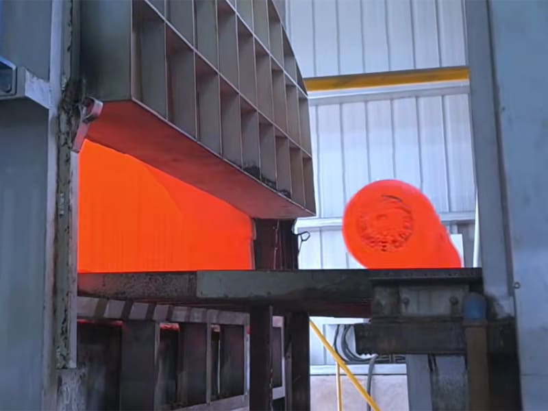 Red‑hot forging part being transported out from industrial heating furnace