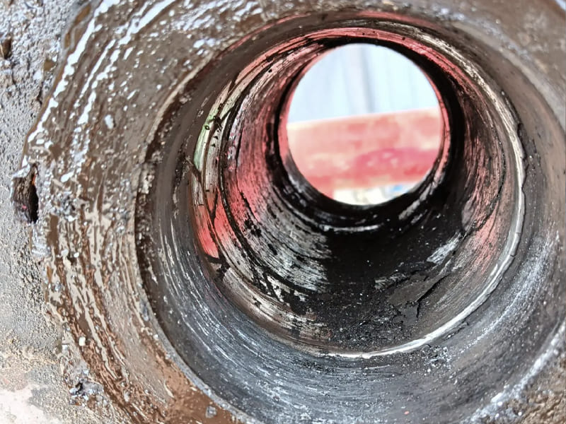 Close‑up view of worn hydraulic cylinder inner bore, scratches and black dirt visible inside the tube