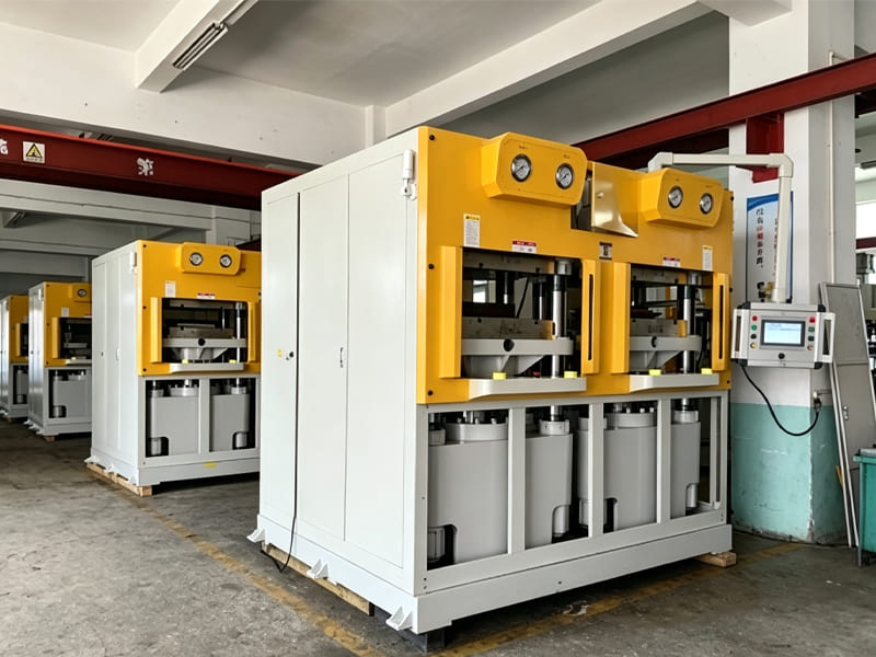 Row of double‑station hydraulic press machines inside factory workshop with pressure gauges and control panel