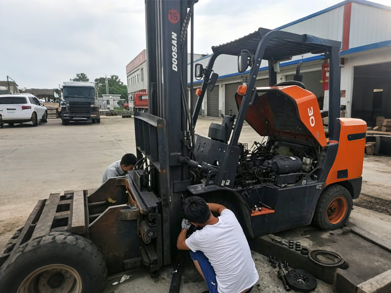 Two technicians repairing the hydraulic components of a Doosan forklift outdoors