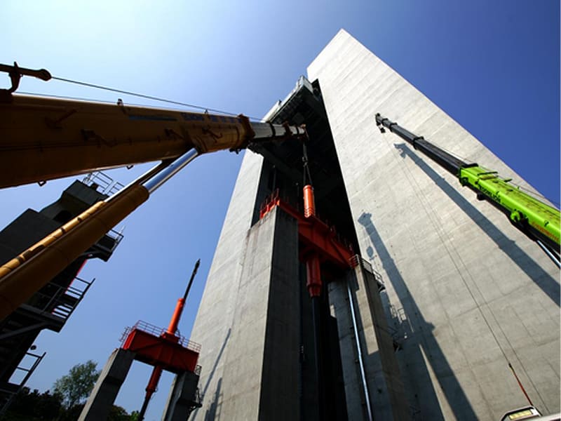 Large‑tonnage hydraulic cylinders hoisted by cranes for building jack‑up construction