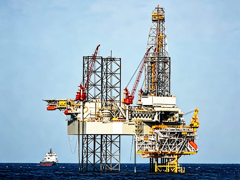 Offshore jack‑up oil drilling platform working on open sea with supply vessel