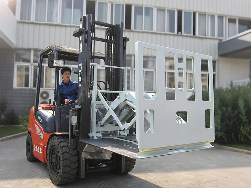 Red HELI forklift with push pull attachment, carrying large white metal panel, operator driving vehicle, factory building in background