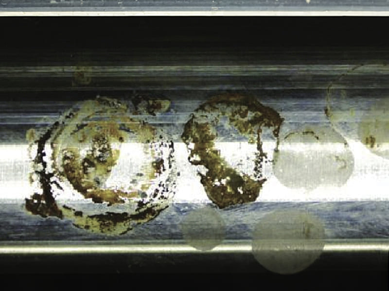 Micro close-up of hydraulic cylinder piston rod, severe rust pitting and coating peeling failure on surface