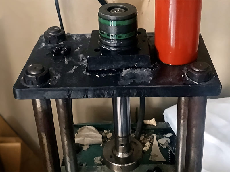 Small hydraulic test fixture for piston seal testing, green composite sealing ring on piston rod, lab testing setup