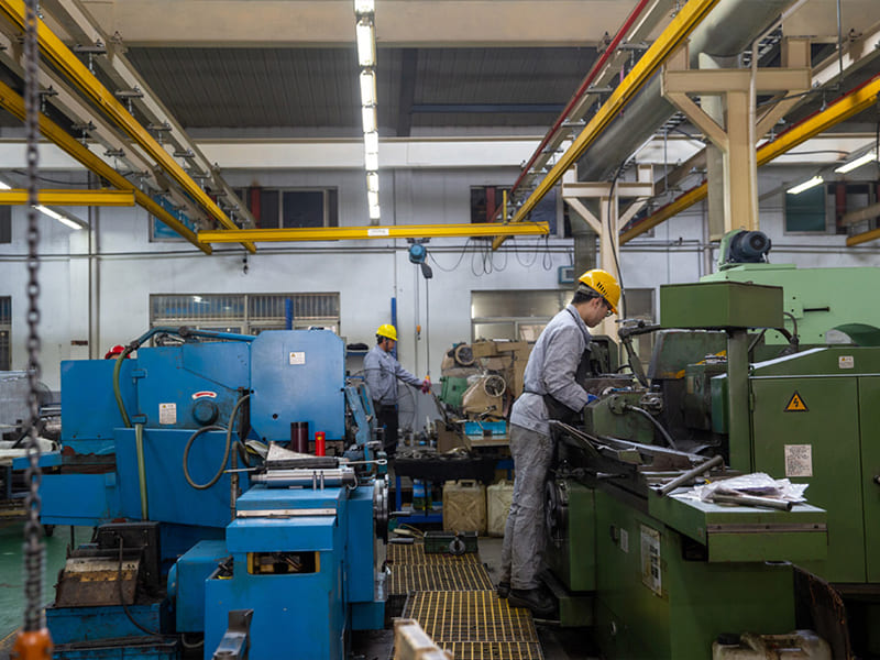 Skilled workers operate lathes and machining equipment to process hydraulic cylinder parts