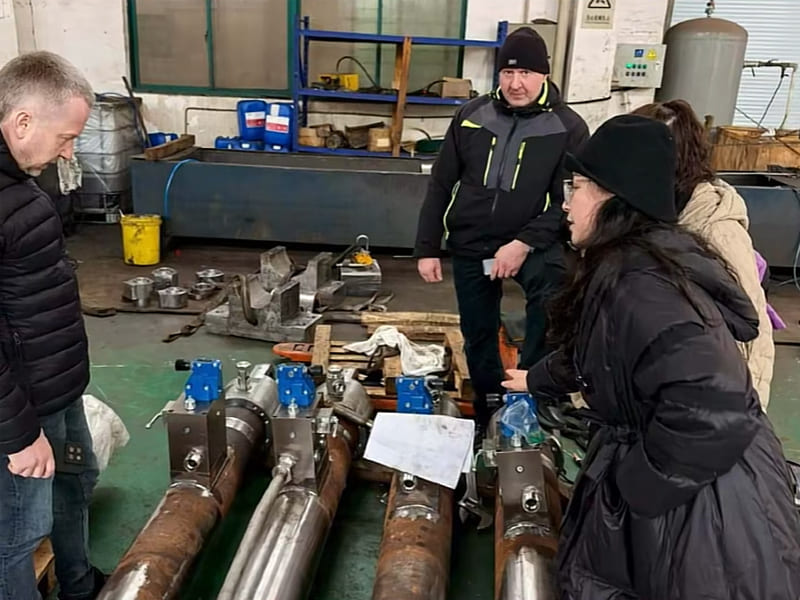 Engineer introduce customized large hydraulic cylinders to overseas customers in workshop