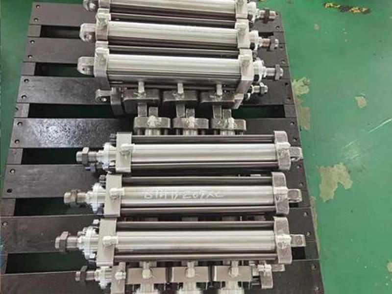Multiple tie rod hydraulic cylinders neatly placed on fixture plate in workshop