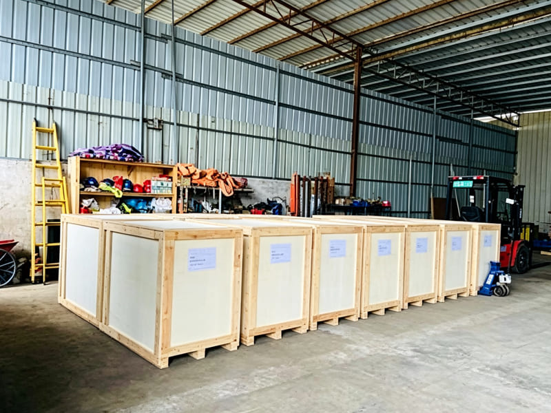 Row of finished wooden packing cases for hydraulic cylinders inside workshop warehouse