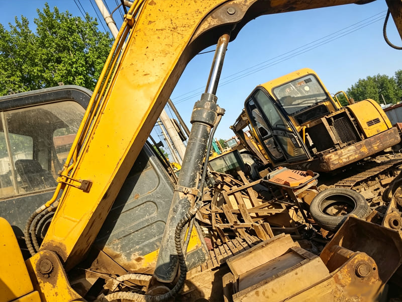 Hydraulic cylinder installed on yellow excavator arm at yard