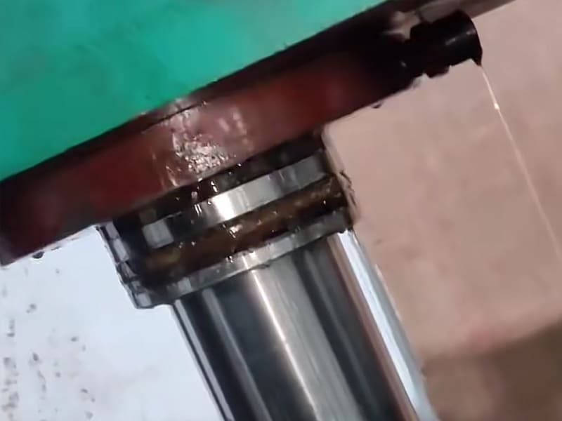 Close‑up view of leaking hydraulic cylinder piston rod with oil dripping out