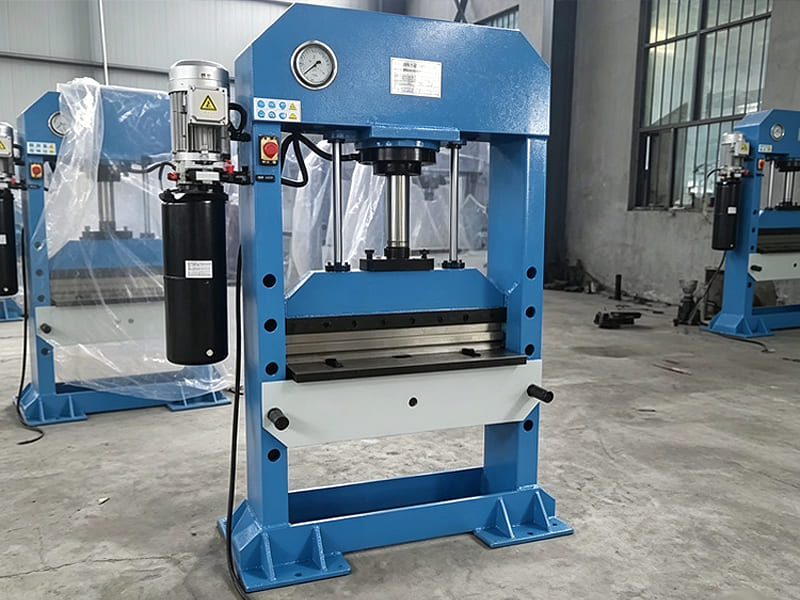 Blue gantry‑type hydraulic press machine with pressure gauge in manufacturing plant