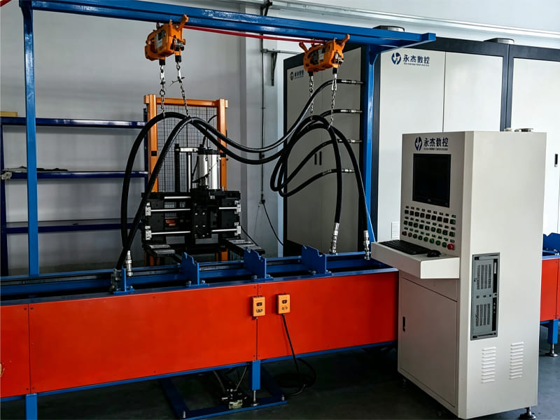 Factory hydraulic test station with control cabinet, overhead hoist and high‑pressure hoses for cylinder testing