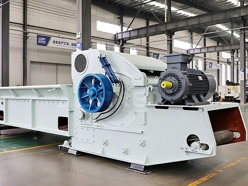 Large industrial wood shredder with long feeding conveyor installed in workshop floor