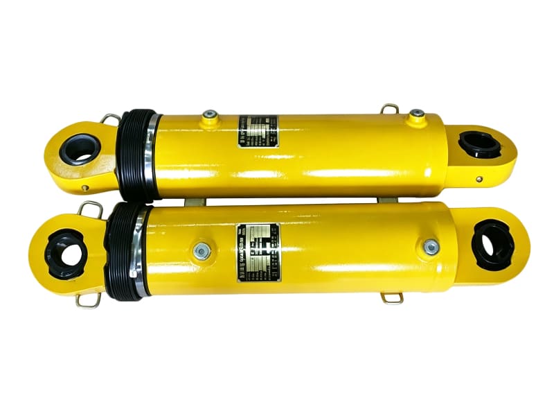 Two yellow hydraulic cylinders side‑by‑side, eye mount ends, rubber dust boot and metal nameplate