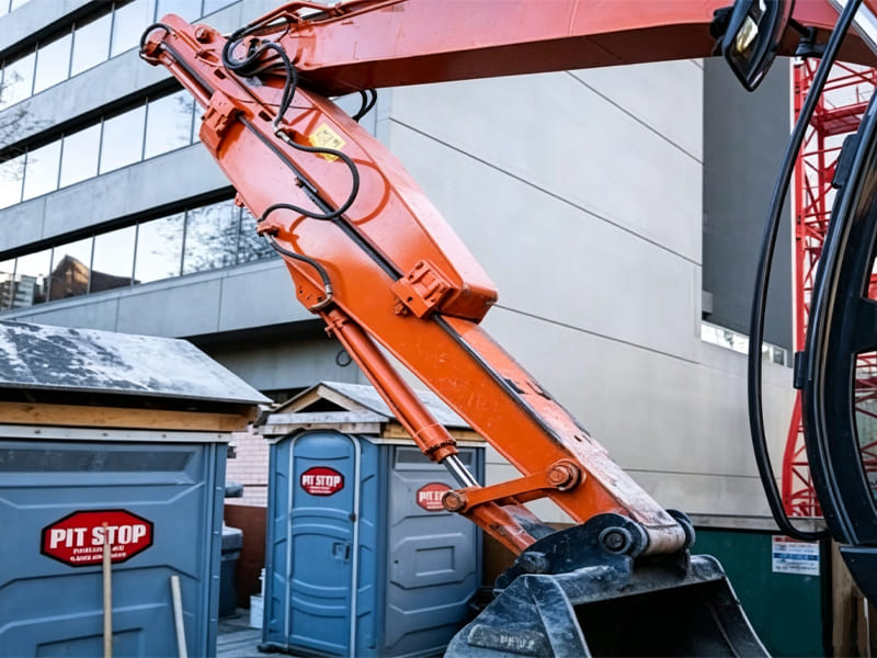 Orange construction excavator arm showing hydraulic hose routing details
