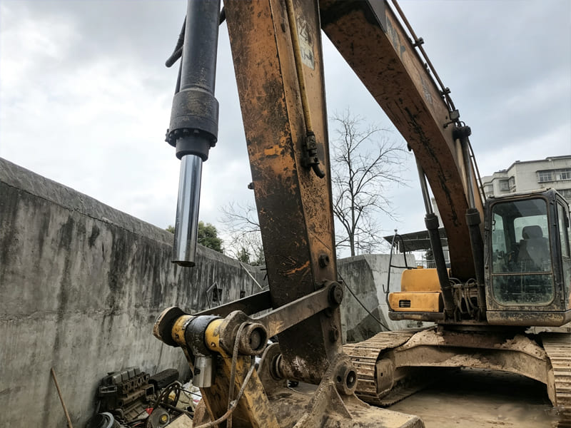 Worn old excavator with extended stick hydraulic cylinder at repair yard