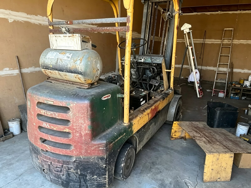 Aged worn‑out forklift disassembled for repair inside maintenance workshop