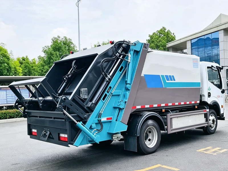 Rear view of compression garbage truck, showing loading mechanism and hydraulic cylinders