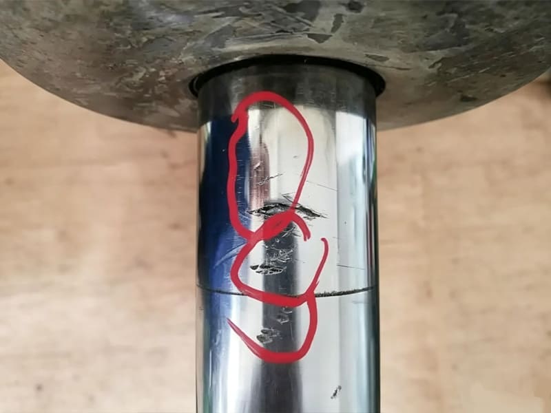 Close‑up photo of hydraulic cylinder piston rod with surface scratch and dent damage