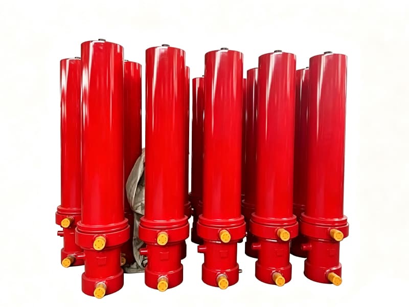 Group of finished red multi‑stage hydraulic cylinders ready for delivery, white background