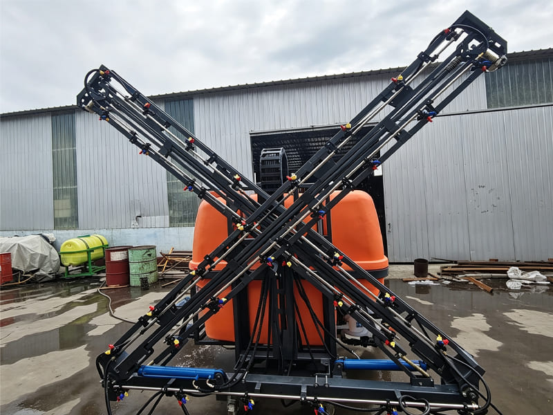 Tractor‑mounted farm boom sprayer with folding spray arms in factory yard