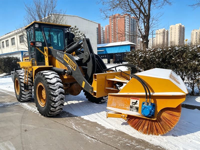 Yellow wheel loader fitted with rotary snow broom, winter road snow cleaning machine