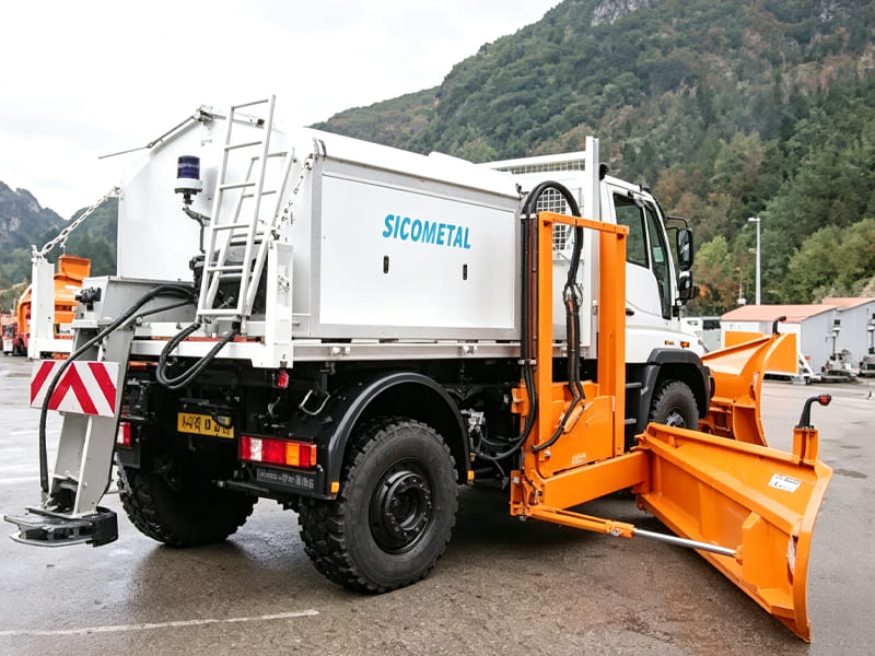 White offroad truck equipped with orange snow plow blade, municipal snow removal vehicle