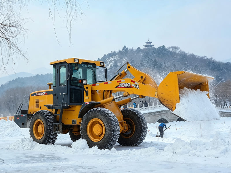 XCMG yellow wheel loader moving snow with bucket, outdoor snow clearing work