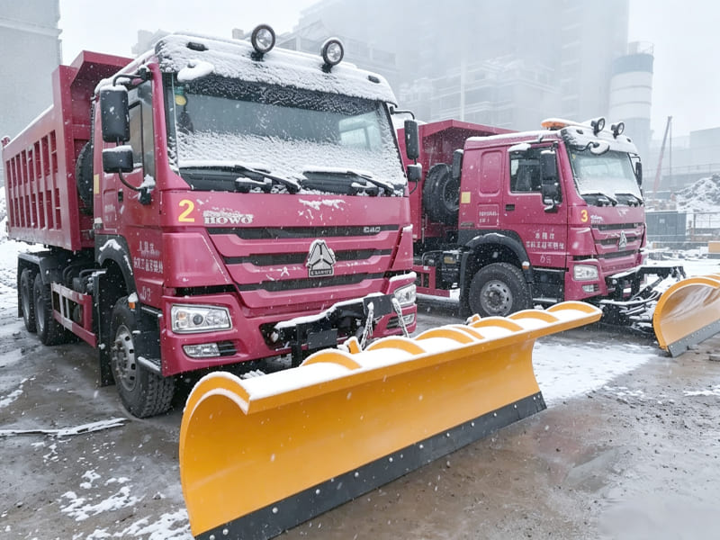 Red HOWO tipper truck fitted with V shape snow plow for heavy snow removal
