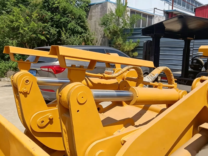 Close-up view of hydraulic cylinder assembly on yellow wheel loader arm