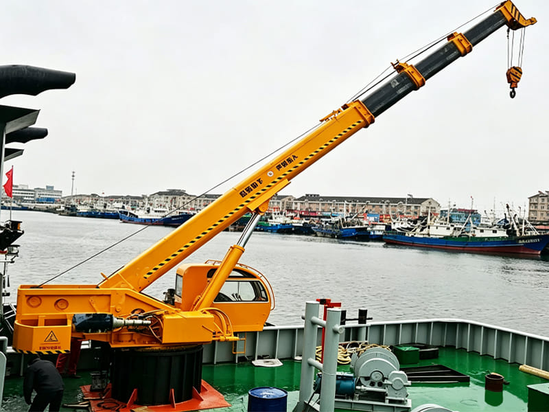 Yellow marine hydraulic crane mounted on vessel deck