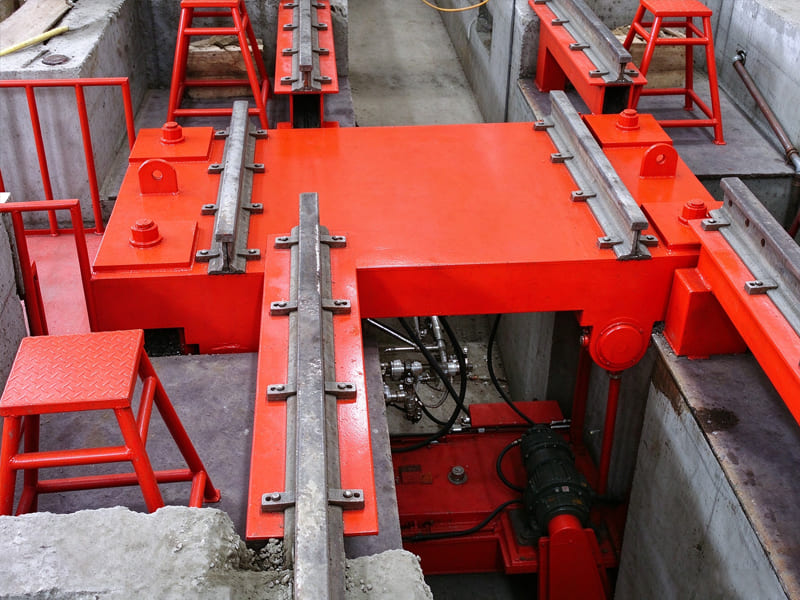 Red pit-mounted railway lifting platform installed in maintenance trench, heavy-duty railcar hoisting equipment