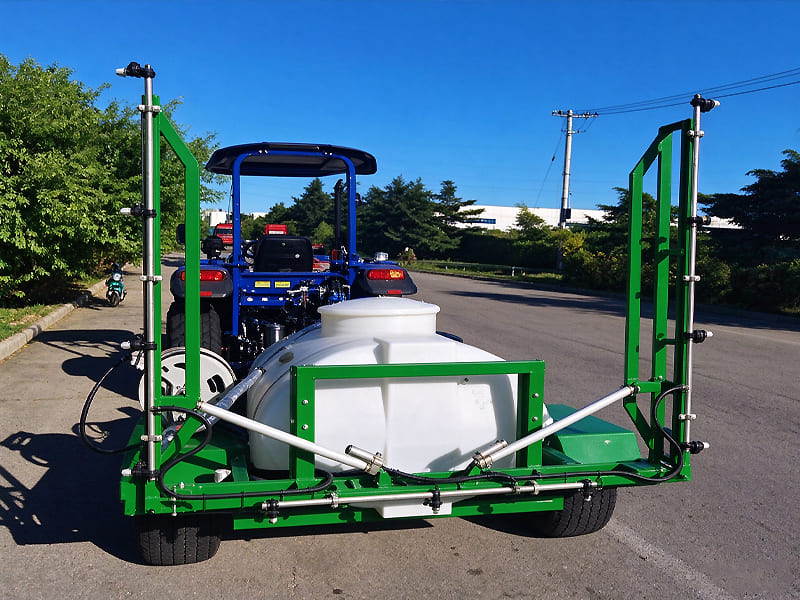 Blue tractor with rear mounted green agricultural boom sprayer, white liquid tank for crop pesticide spraying, outdoor road shot