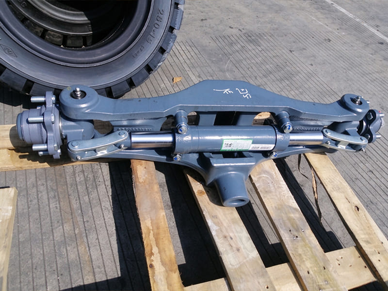 Grey forklift steering axle assembly with horizontal hydraulic steering cylinder, mounted on wooden pallet