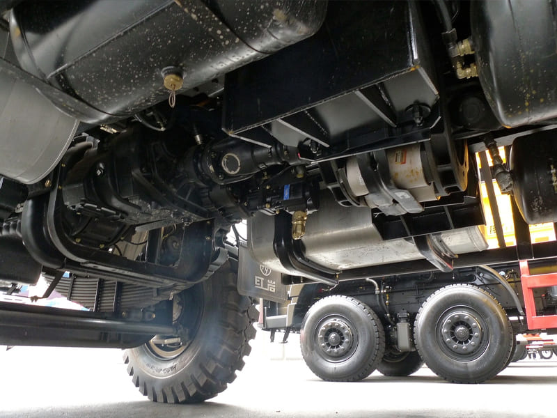 Undercarriage view of heavy off-road truck, showing suspension and hydraulic system parts