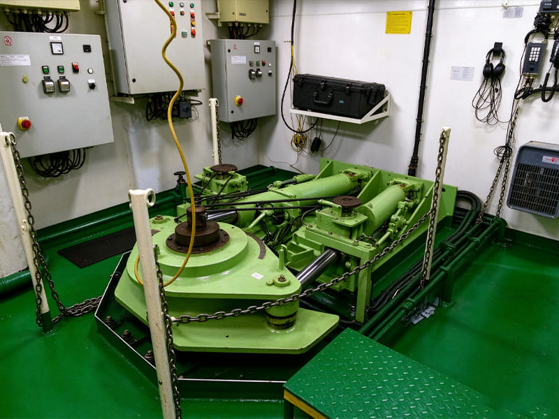 Green marine hydraulic steering cylinder unit inside ship engine control room, ship rudder hydraulic system