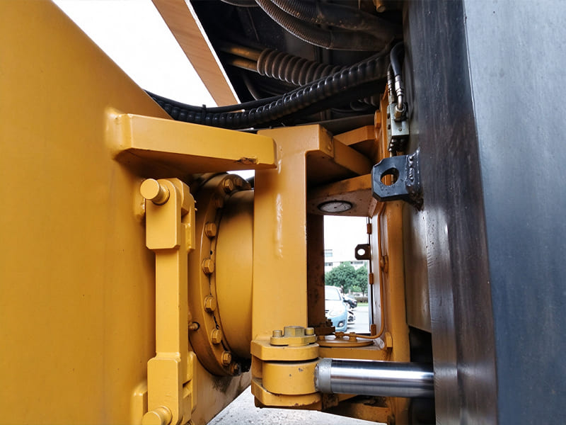 Close-up of hydraulic cylinder at the hinge joint of yellow road roller construction machine