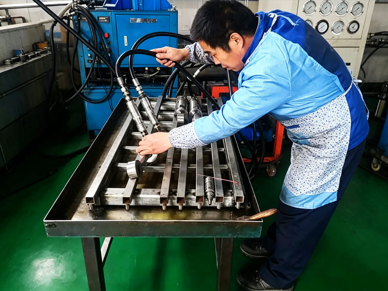 Technician connects hydraulic hoses to test bench for hydraulic cylinder pressure performance testing