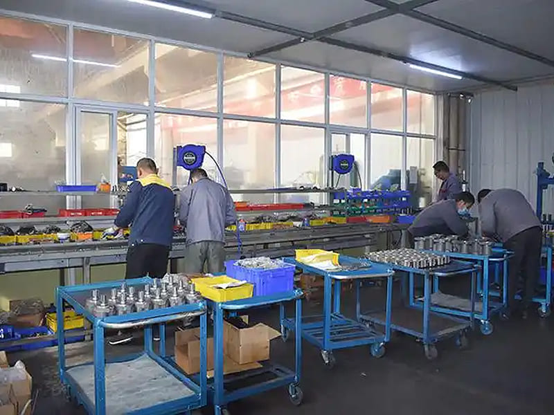 Workers assembling hydraulic cylinders in production workshop with assembly lines